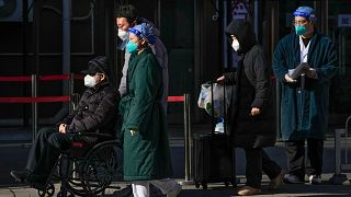 Medical workers in protective gear escort an elderly patient on a wheelchair followed by family members as they leave a fever clinic at a hospital in Beijing. 
