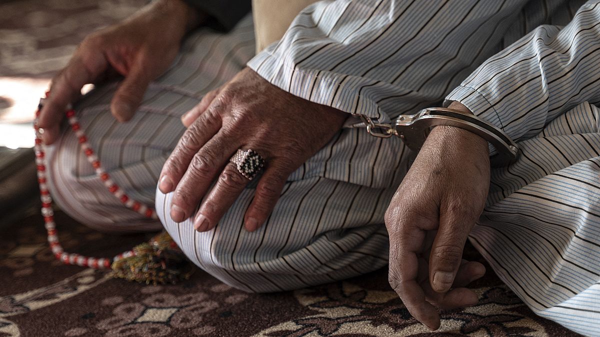رجل أفغاني محكوم عليه بالإعدام بتهمة القتل، مكبل اليدين إلى سجين آخر، خلال جلسة استماع في محكمة استئناف غزني، في شرق أفغانستان. 2022/11/28