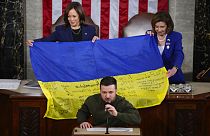 La vicepresidenta Kamala Harris y la presidenta de la Cámara de Representantes, Nancy Pelosi, sujetan una bandera ucraniana firmada por las tropas en Bajmut