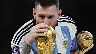 الأرجنتيني ليونيل ميسي يقبل كأس العالم بكأس الكرة الذهبية في يده بعد المباراة النهائية لكأس العالم لكرة القدم بين الأرجنتين وفرنسا على ملعب لوسيل في قطر. 2022/12/18