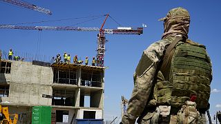 A Russian soldier guards the site of a new apartment building which is is being built with the support of the Russian Defence Ministry, in Mariupol, July 2022