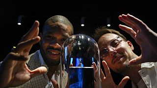 Calvin Jong-A-Pin, sales and marketing specialist at Gassan Diamonds, left, and artist Pablo Lücker, right, pose with the smallest work of art on a diamond, an engraved heart.