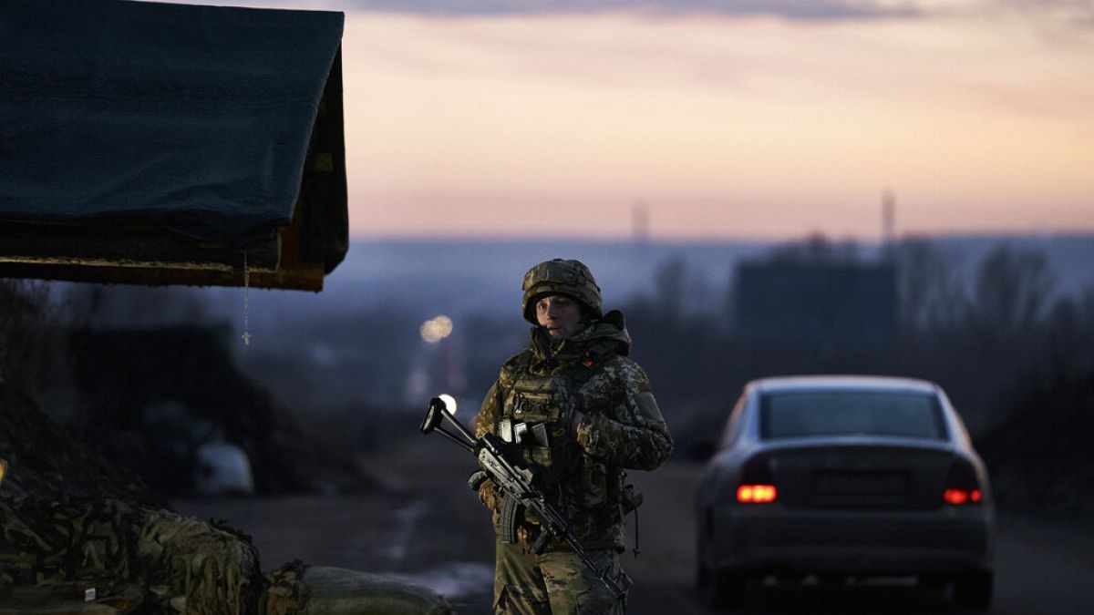 Egy ukrán katona áll egy ellenőrzőpontnál, miközben a nap lenyugszik Kramatorszkban, Donyeck régióban, Ukrajnában, 2022. december 22-én.