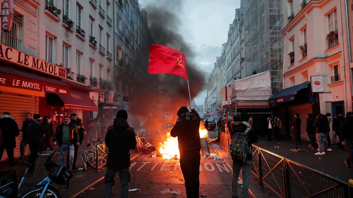 members of Kurdish community waves the Kurdish communist flags next to a barricade on fire at the crime scene where a shooting took place in Paris, Friday, Dec. 23, 2022. 
