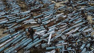 A war prosecutor observes collected parts of Russian rockets which were used to attack the city of Kharkiv, in Kharkiv, Ukraine, Thursday, Dec. 22, 2022.