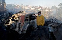 Egy chilei férfi áll kiégett autója előtt