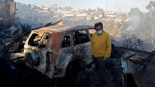 Egy chilei férfi áll kiégett autója előtt