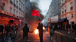 Ein Mitglied der kurdischen Gemeinschaft schwenkt die Fahnen der kurdischen Kommunisten neben einer brennenden Barrikade am Tatort einer Schießerei in Paris