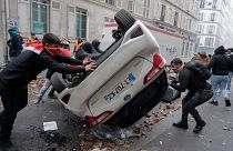 Manifestantes vuelcan un coche durante una protesta contra el reciente tiroteo en el centro cultural kurdo de París, el 24 de diciembre de 2022. 