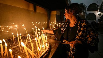 A woman lights candles inside the Church of the Nativity, traditionally believed to be the birthplace of Jesus Christ, in the West Bank town of Bethlehem,Saturday , Dec. 24, 2