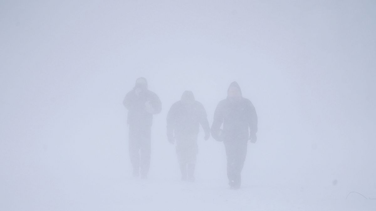 ثلاثة أشخاص يسيرون وسط الثلوج الكثيفة التي غطت بافالو في نيويورك