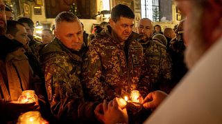 Украинские военнослужащие получают Вифлеемский огонь во время рождественской службы в Харькове, 25 декабря 2022 года.