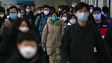 Masked commuters walk in between two subway stations as they head to work during the morning rush hour in Beijing, Tuesday, December 20, 2022.
