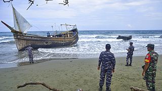 Des militaires indonésiens inspectent un bateau en bois utilisé pour transporter des réfugiés rohingyas.