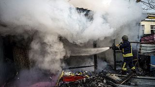 A rescuer extinguishes a fire in a burning shop after Russian shelling to Ukrainian city of Kherson, 24 December 2022