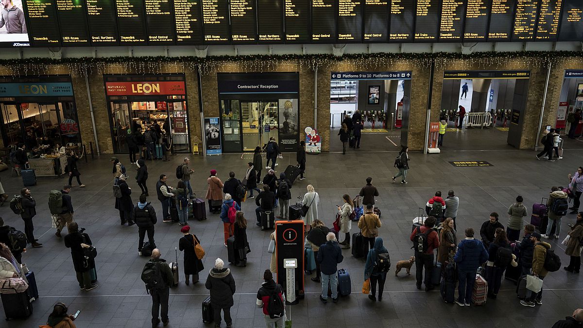 Varias personas se preparan para subir a un tren en la estación londinense de Kings Cross, el sábado 24 de diciembre de 2022.