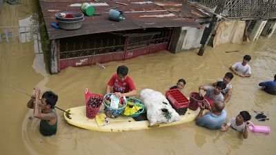 Des habitants donnent des oignons et d'autres aliments le long d'une route inondée par le typhon Noru dans la ville de San Miguel, Philippines