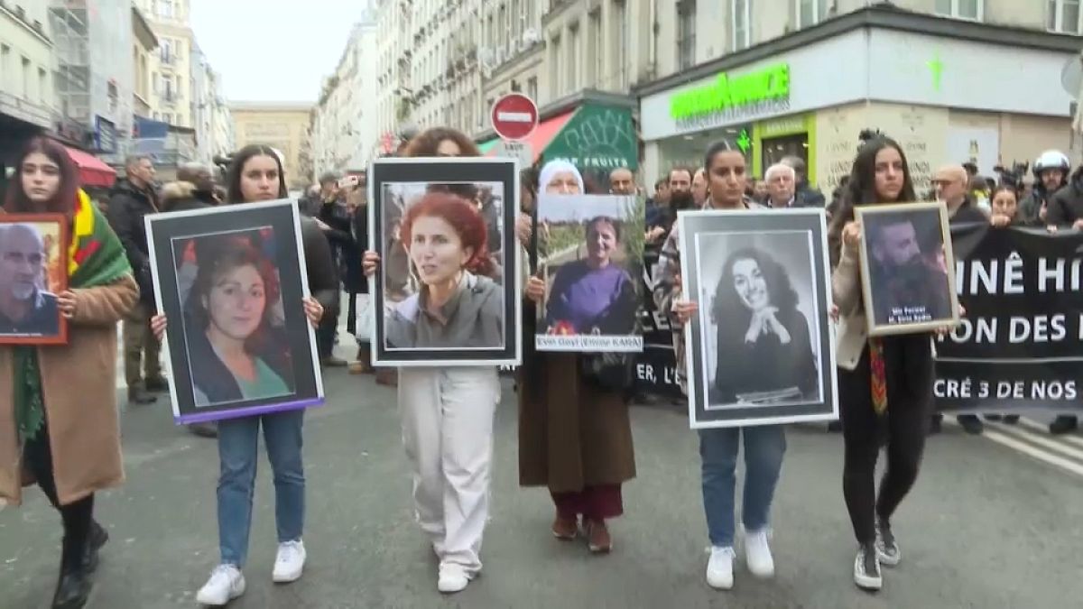 Demonstrators hold portraits of victims of the Enghien Street shooting in Paris on 23 December 2022, and those of La Fayette street murders in 2013.