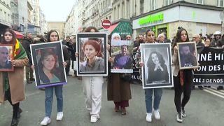 Des manifestants tiennent des portraits des victimes de vendredi et de trois militantes Kurdes tuées en 2013 dans le même quartier.