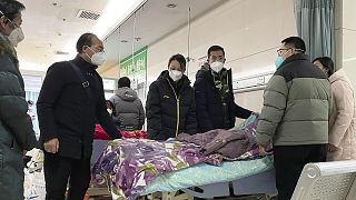 A man pulls a cloth to cover up the face of an elderly woman whose vitals flatlined as relatives gather for a final farewell in Bazhou, Hebei province, 22 December 2022