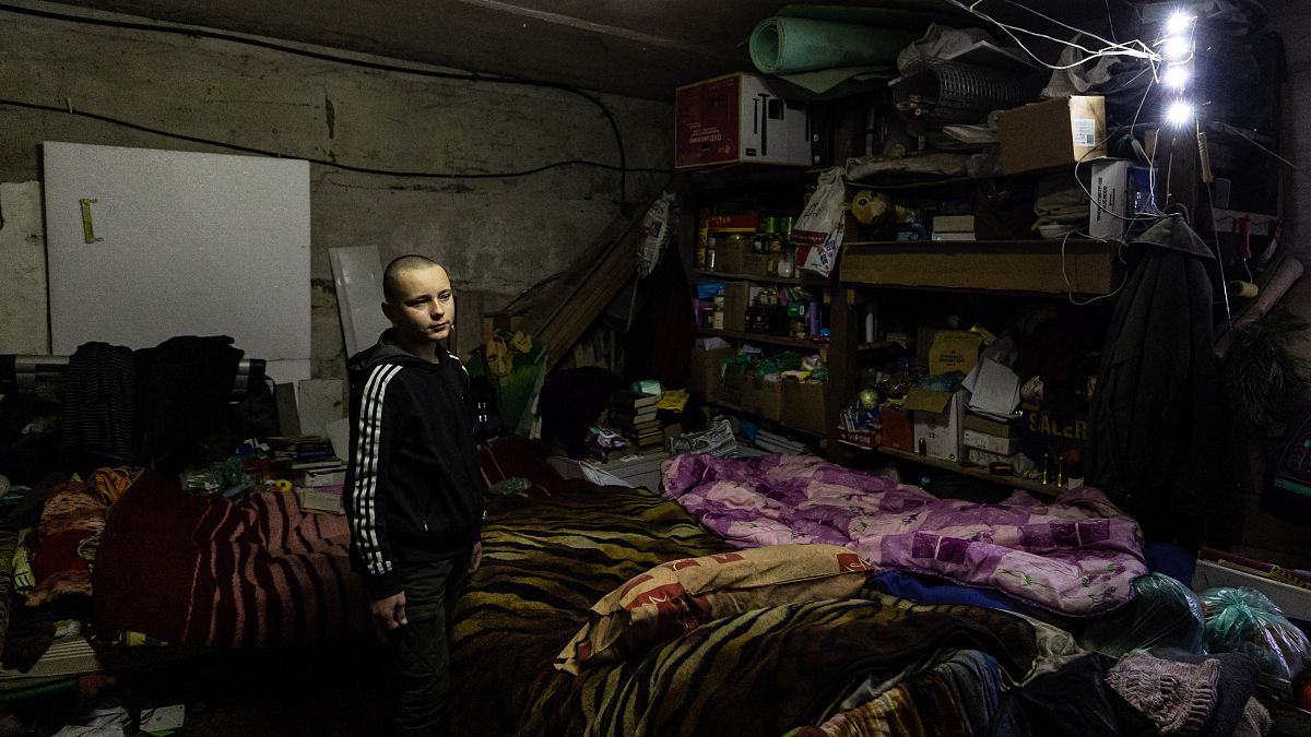 جليب بيتروف، البالغ من العمر 14 عامًا، يجلس مع عائلته في قبو في مدينة باخموت بشرق أوكرانيا في 21 ديسمبر/كانون الأول 2022.
