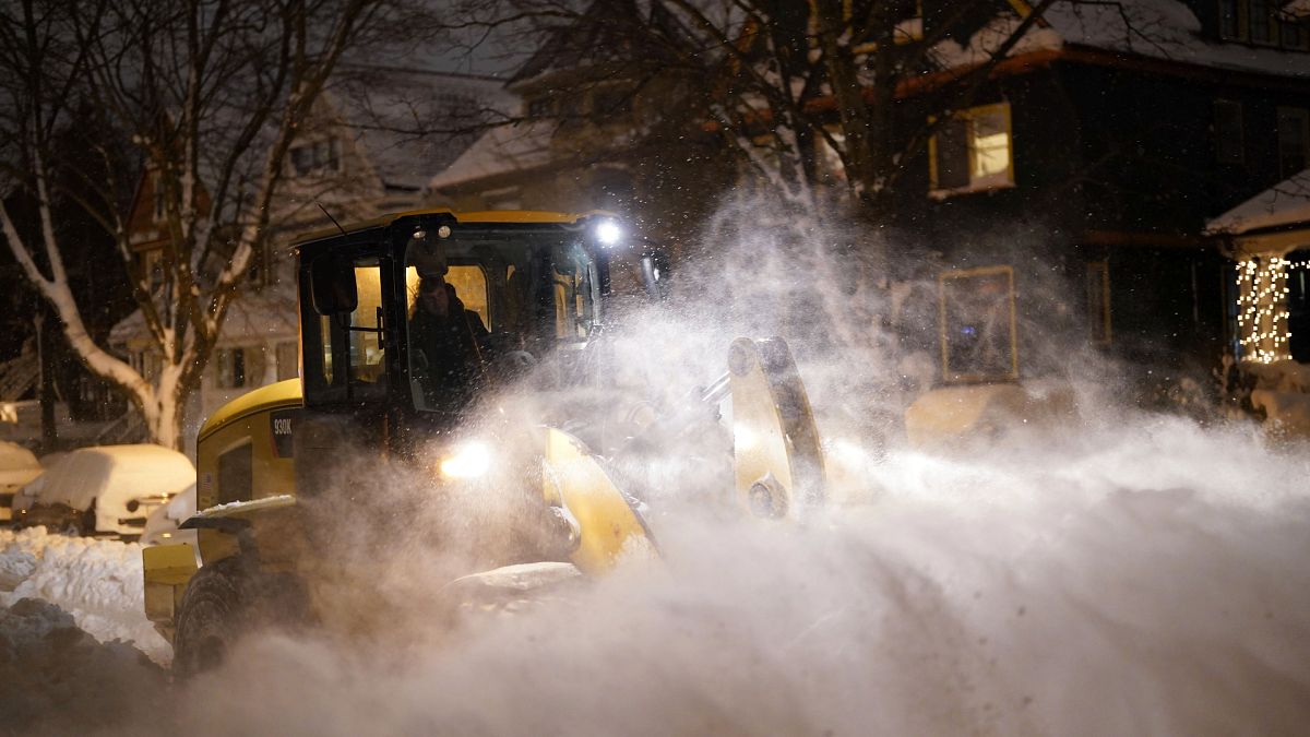 A city worker in a wheel loader clears snow on Norwood Avenue as crews work through the night to reopen the city after a deadly blizzard over the weekend.