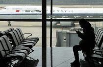 A passenger checks her phone as an Air China jet taxies past at the Beijing Capital International airport in Beijing, 29 October 2022