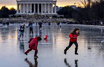 People walk over the frozen Reflecting Pool on the National Mall in Washington, DC, as a historic winter storm and Arctic blast engulf the US.