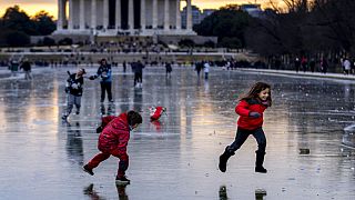 People walk over the frozen Reflecting Pool on the National Mall in Washington, DC, as a historic winter storm and Arctic blast engulf the US.