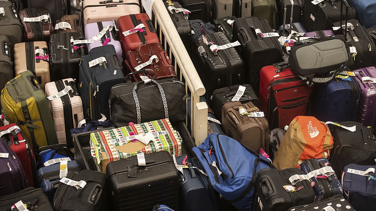 Hundreds of unclaimed suitcases and a box wrapped in Christmas wrapper sit near the baggage carousel at Midway Airport in Chicago, 27 December 2022