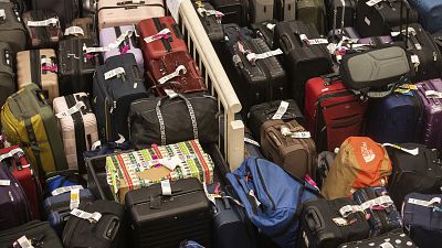 Hundreds of unclaimed suitcases and a box wrapped in Christmas wrapper sit near the baggage carousel at Midway Airport in Chicago, 27 December 2022