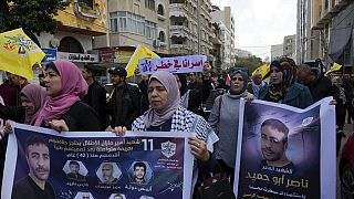  فلسطينيون يحملون ملصقات لناصر أبو حميد، أسير فلسطيني توفي بسرطان الرئة في الحجز الإسرائيلي الأسبوع الماضي، في مدينة غزة، 27 ديسمبر 2022.