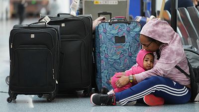 A stranded passenger holds her 14-month-old daughter as she waits with family members at the Southwest terminal at the Los Angeles International Airport.