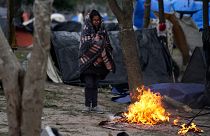 A migrant stands in the cold weather around a fire at a makeshift camp on the U.S.-Mexico border in Matamoros, Mexico. 