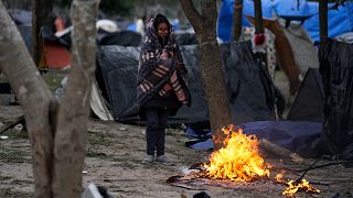 A migrant stands in the cold weather around a fire at a makeshift camp on the U.S.-Mexico border in Matamoros, Mexico. 