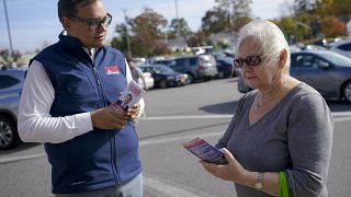 Republican candidate for New York's 3rd Congressional District George Santos, left, talks to a voter while campaigning outside a Stop and Shop store, 5 November 2022