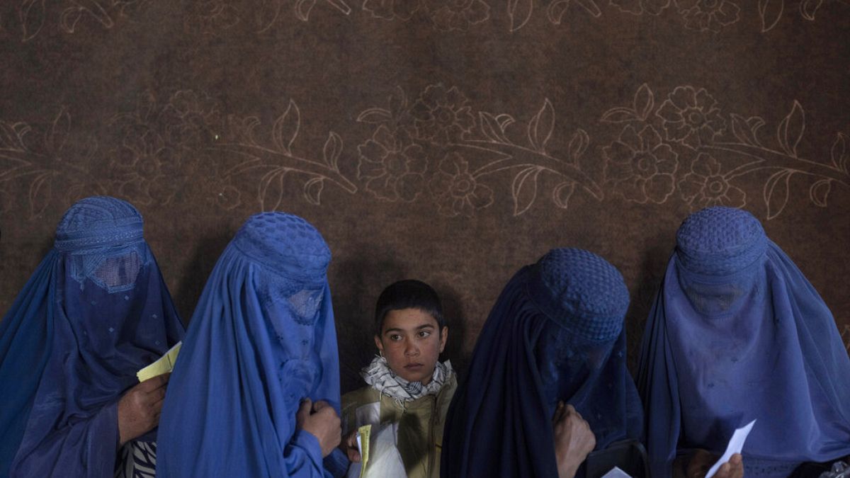 Mujeres afganas esperan para recibir dinero en un punto de distribución organizado por el Programa Mundial de Alimentos, en Kabul, Afganistán.