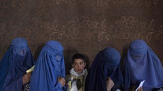 Mujeres afganas esperan para recibir dinero en un punto de distribución organizado por el Programa Mundial de Alimentos, en Kabul, Afganistán.