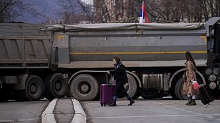 Pedestrians walk past a new road barricade set up in the divided town of Mitrovica on December 28, 2022. 