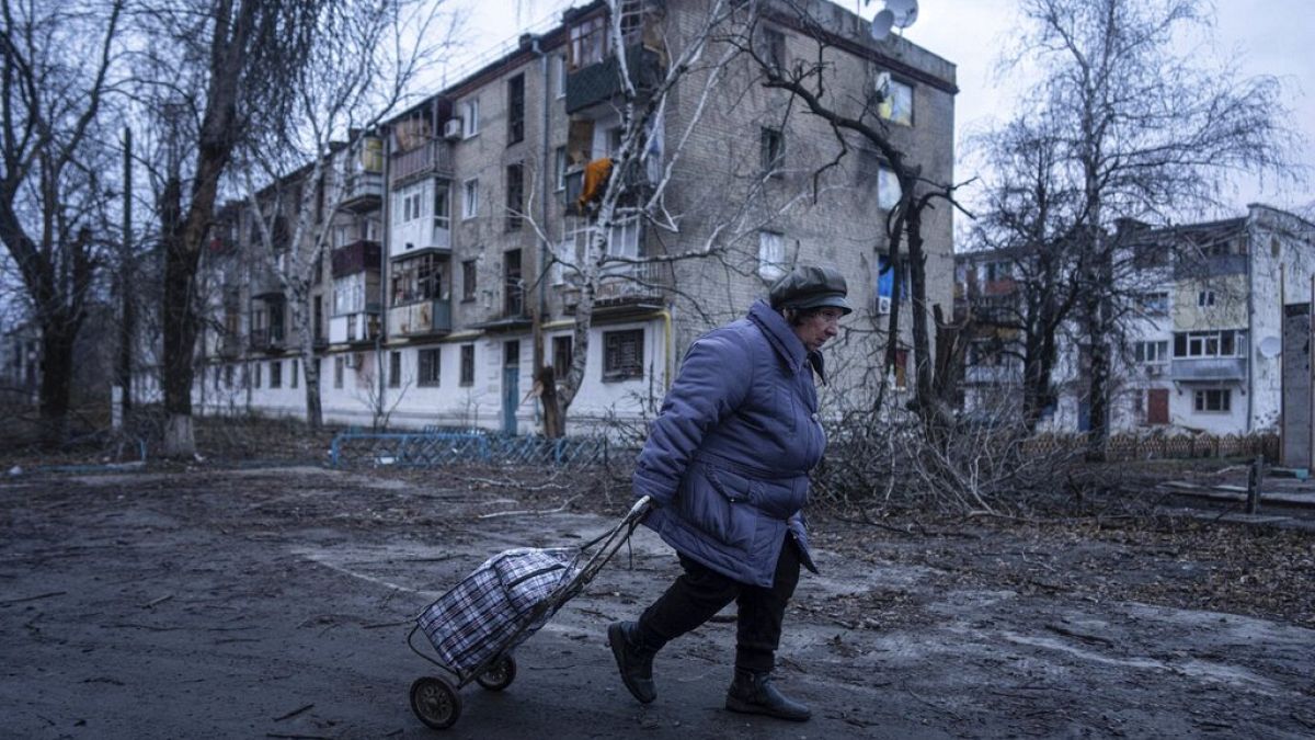 A woman walks to a humanitarian aid distribution point in front of a block which was damaged by Russian shelling in Kupiansk, Kharkiv on Wednesday, December 28.