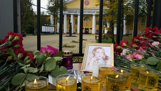 Flowers, candles and a portrait of one of victims are displayed on a table outside the Perm State University.