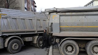 Un hombre pasa junto a una barricada de camiones cargados de piedras en una calle del norte de la ciudad de Mitrovica, Kosovo, dominada por los serbios.