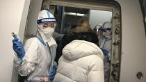 Cabin crew wearing protective gear greet and check the temperatures of travelers heading to China onboard a flight from the JFK airport in New York on Dec. 24, 2022.