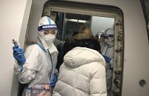 Tripulantes de cabina con equipos de protección saludan y comprueban la temperatura de los viajeros que se dirigen a China a bordo de un vuelo procedente del aeropuerto JFK