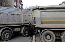 A man passes by a barricade made of trucks loaded with stones on a street in northern, Serb-dominated part of ethnically divided town of Mitrovica, Kosovo, 28 December 2022