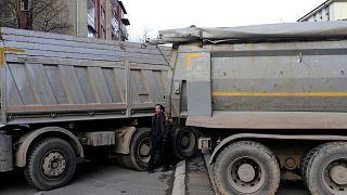 A man passes by a barricade made of trucks loaded with stones on a street in northern, Serb-dominated part of ethnically divided town of Mitrovica, Kosovo, 28 December 2022