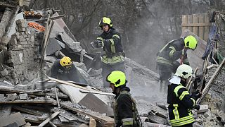 Rescuers clear debris of homes destroyed by a missile attack in the outskirts of Kyiv, on December 29, 2022