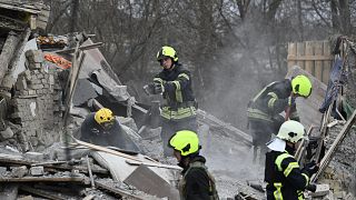 Mentőegységek takarítják a rakétatámadásban  megsemmisült házak romjait Kijev külvárosában 2022. december 29-én