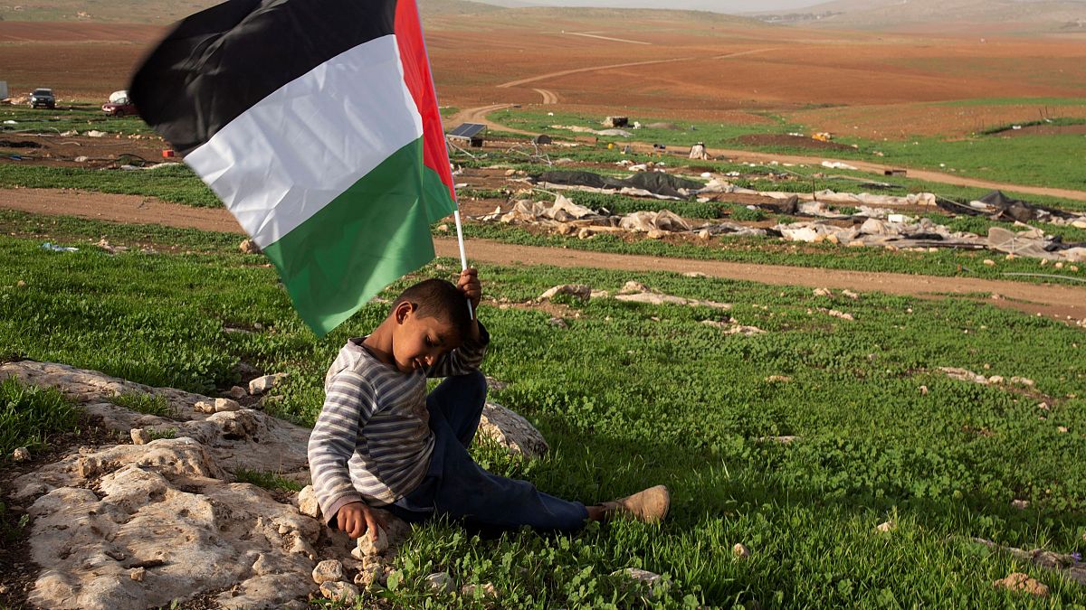 طفل فلسطيني يحمل العلم الفلسطيني بعد أن هدمت القوات الإسرائيلية الخيام وغيرها من المباني في قرية خربة حمسو في غور الأردن في الضفة الغربية. 2021/02/03