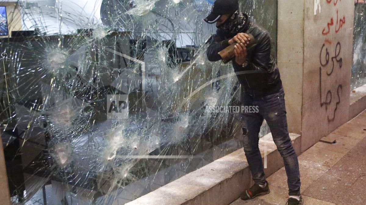 Un manifestante distrugge la vetrina di una banca, durante le proteste contro il governatore della Banca centrale libanese ad Hamra trade street, a Beirut, Libano, 14 gennaio.